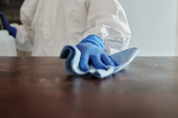 Free Person in protective suit using disinfectant on surface to ensure cleanliness and safety. Stock Photo